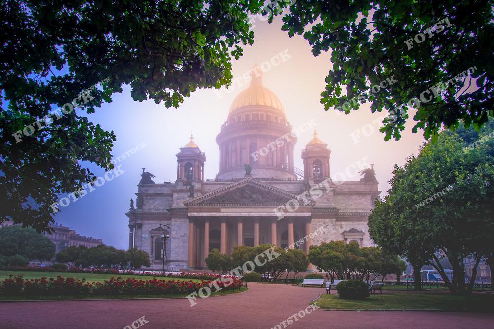 На фотографии изображен Исаакиевский собор в Санкт-Петербурге, одна из самых величественных и известных архитектурных достопримечательностей города. Солнечное утро придает особую теплоту изображению, а зелень деревьев, обрамляющая собор, создает эффект уюта и спокойствия. Парковая зона перед собором украшена цветами, что добавляет яркости в общую композицию.